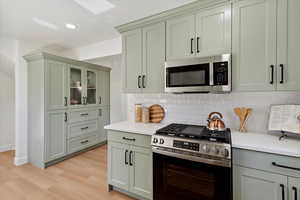 Kitchen with stainless steel appliances, light wood-type flooring, light countertops, decorative backsplash, and recessed lighting
