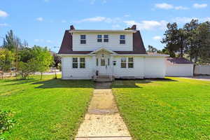 View of front of home with a chimney, a front yard, and a detached garage