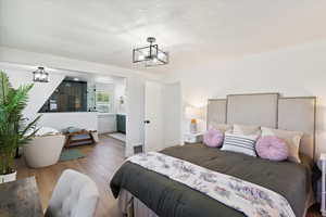 Bedroom featuring a chandelier, wood finished floors, and ensuite bathroom