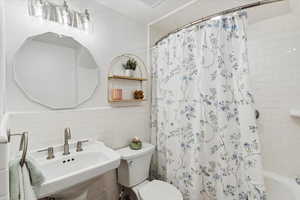 Bathroom with tile walls, shower / bath combo with shower curtain, and a wainscoted wall