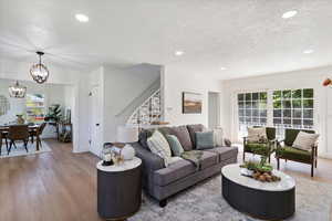 Living area featuring stairway, wood finished floors, a chandelier, healthy amount of natural light, and recessed lighting