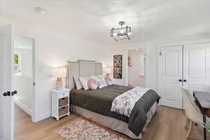 Bedroom with light wood-style floors, a chandelier, and a closet