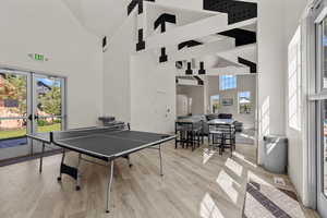 Game room featuring high vaulted ceiling, light wood-style floors, beamed ceiling, and french doors