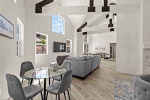 Dining area with beamed ceiling, high vaulted ceiling, and light wood-style flooring