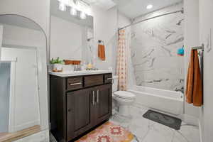 Bathroom with marble look tile flooring, vanity, shower / tub combo with curtain, and recessed lighting