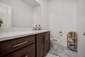 Half bathroom with marble finish flooring and vanity