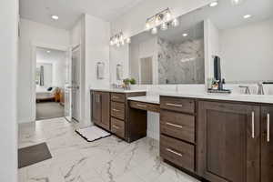 Ensuite bathroom featuring a marble finish shower, vanity, marble look tile flooring, and recessed lighting