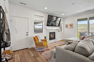 Living area featuring wood finished floors, a premium fireplace, recessed lighting, and a textured ceiling