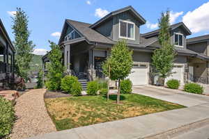 View of front of property with a front lawn, an attached garage, driveway, and board and batten siding