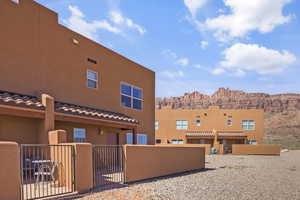 Back of property featuring a tiled roof, stucco siding, a gate, and a mountain view