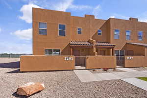 View of front of house with a fenced front yard, a gate, stucco siding, and a tile roof