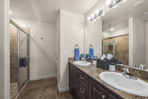 Full bathroom with double vanity, a stall shower, and tile patterned flooring