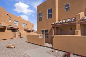 View of front of property with a fenced front yard, a gate, stucco siding, a tiled roof, and a residential view