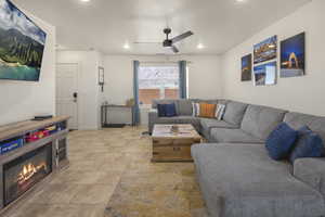 Living room with ceiling fan, recessed lighting, a glass covered fireplace, and light tile patterned floors