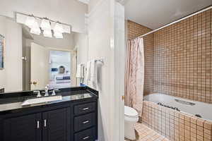 Full bath with tile patterned flooring, vanity, and tiled shower / bath combo