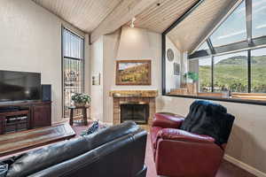 Living area with wood ceiling, a textured wall, and a tiled fireplace