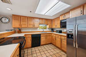 Kitchen featuring black appliances, light countertops, light tile patterned flooring, and recessed lighting