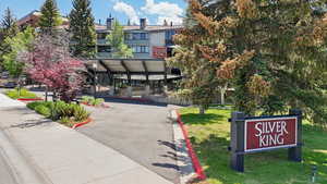 Surrounding community with asphalt driveway, a yard, and a carport