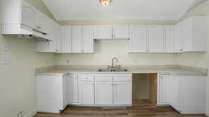 Kitchen with dark wood-style floors, white cabinetry, and vaulted ceiling
