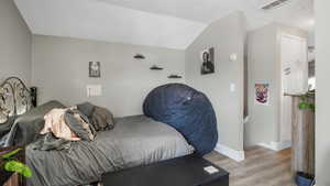 Bedroom featuring wood finished floors and vaulted ceiling