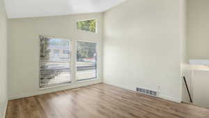 Unfurnished room with wood finished floors and high vaulted ceiling
