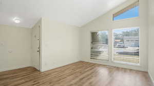 Empty room with light wood-type flooring and vaulted ceiling