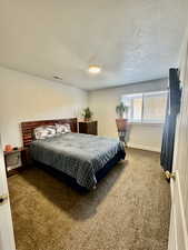 Carpeted bedroom with a textured ceiling and baseboards