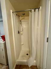 Full bath featuring washer / clothes dryer, a textured ceiling, and a shower stall
