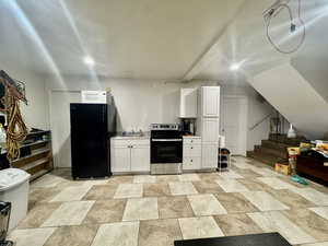 Kitchen featuring stainless steel range with electric cooktop, freestanding refrigerator, white cabinets, light countertops, and stone finish flooring