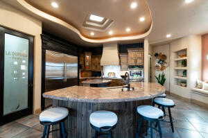 Kitchen featuring a large island with sink, custom exhaust hood, recessed lighting, a kitchen bar, and built in shelves