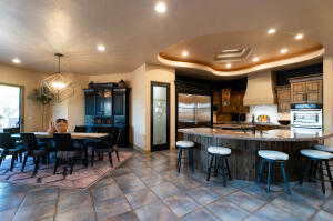 Kitchen featuring custom range hood, fridge, stainless steel double oven, a kitchen breakfast bar, and recessed lighting