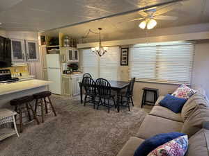 Dining area featuring carpet flooring, lofted ceiling, a ceiling fan, and a chandelier