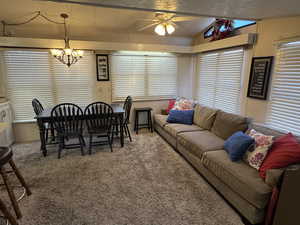 Carpeted dining space featuring a ceiling fan, lofted ceiling, healthy amount of natural light, and a chandelier