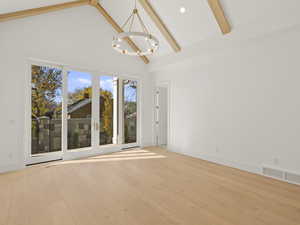 Unfurnished room featuring high vaulted ceiling, beamed ceiling, light wood-type flooring, and a chandelier
