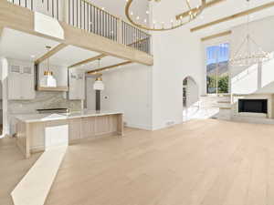 Kitchen featuring hanging light fixtures, a chandelier, glass insert cabinets, beamed ceiling, and open floor plan