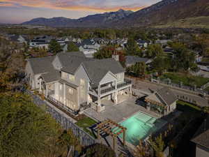 Aerial view at dusk of a mountain view, view of pool, and a residential view