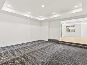 Spare room featuring a tray ceiling, recessed lighting, and dark colored carpet