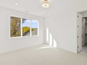 Empty room with light colored carpet and recessed lighting