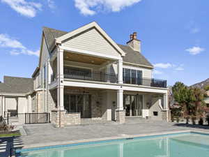 Back of house featuring a patio area, an outdoor pool, and a balcony