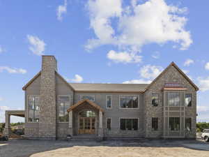 Rear view of house featuring stone siding and a chimney