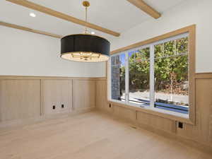 Unfurnished dining area featuring a wainscoted wall, beam ceiling, light wood finished floors, recessed lighting, and a decorative wall