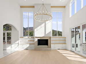 Unfurnished living room featuring french doors, light wood-type flooring, and a high ceiling