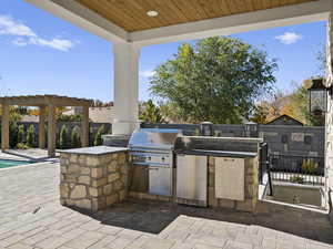 Fenced backyard with a patio area, an outdoor kitchen, and a pergola