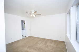 Spare room featuring light carpet and ceiling fan