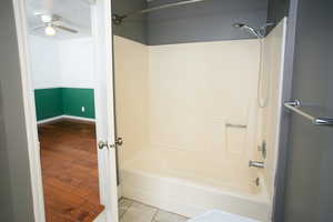 Bathroom featuring shower / bathtub combination, a ceiling fan, and wood finished floors