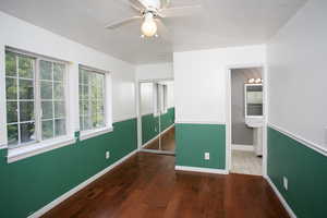 Unfurnished bedroom featuring hardwood / wood-style floors, a closet, a ceiling fan, ensuite bath, and a textured ceiling