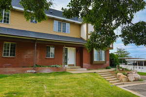 View of front of property with a front lawn, brick siding, and roof with shingles