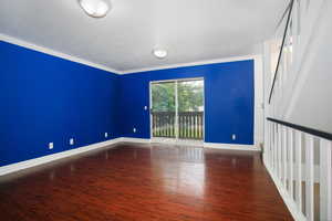 Empty room featuring ornamental molding, wood finished floors, and a textured ceiling