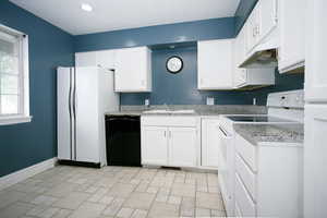 Kitchen with white appliances, white cabinets, light stone finish floors, and recessed lighting
