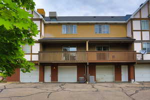 View of front of home featuring an attached garage, driveway, and a balcony